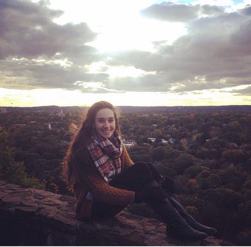 Author Hallie at East Rock, sitting on a stone wall overlooking New Haven.