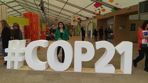 A conference attendee standing behind large block letters reading &quot;#COP21&quot;