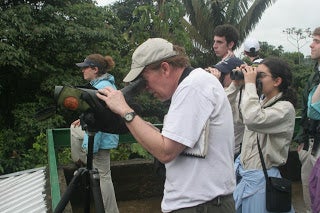 A professor looking intently through a camera.