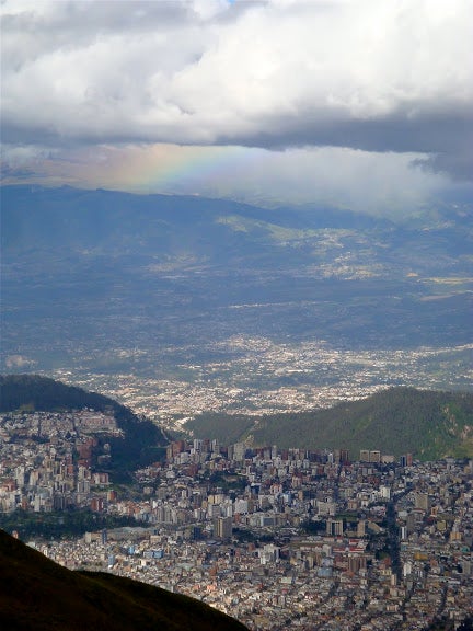 Quito from the top of the Pichincha Volcano, with a rainbow in the sky over the city.