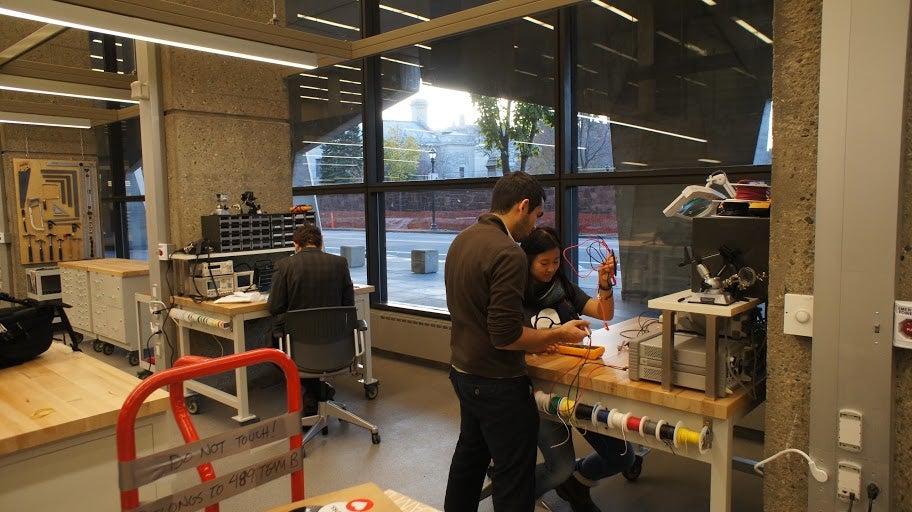 Students working on a project at the electronics benches, featuring spools of different-colored wires.