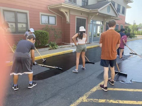 Four individuals paving a driveway.