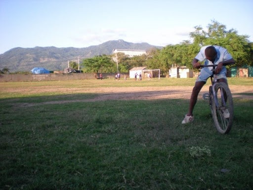 A man on a bicycle resting in an open field.