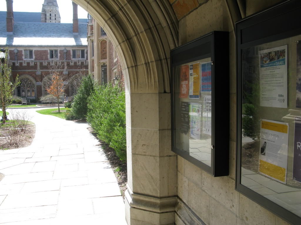 Glass display cases inside a campus gate containing fliers and posters.
