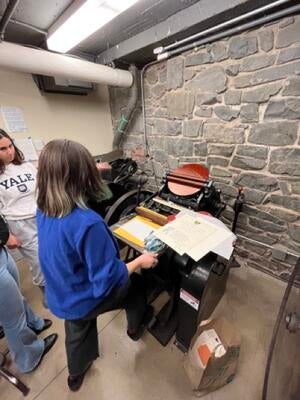 student staff demonstrating the use of printing press for mass production