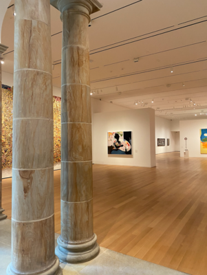 Interior on an art gallery with modern paintings displayed and a grand ornate pillar