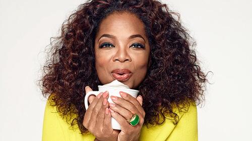 Oprah drinking a coffee and posing for the camera.