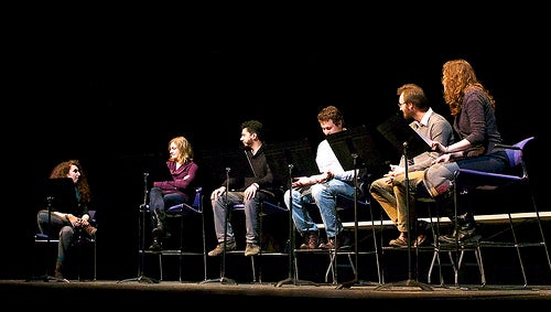 A small cast reading a play aloud onstage.