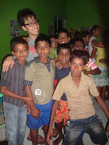 A student posing with a large group of young children.