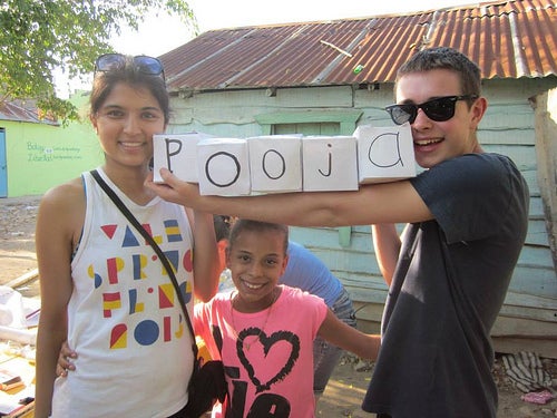 Pooja and Adam with a young girl, holding alphabet cubes spelling &quot;Pooja&quot;.