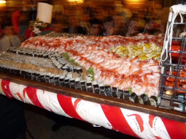 A buffet table stuffed with sushi and shrimp in the shape of a letter Y.