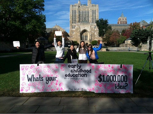 A sign covered in paint handprints reading &quot;What's your $1,000,000 idea?&quot;