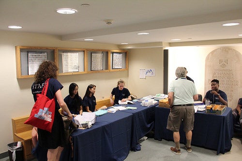 Students manning a check-in desk assist an older Yale alumnus.