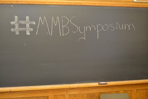 Classroom blackboard reading &quot;#MMBSymposium&quot;