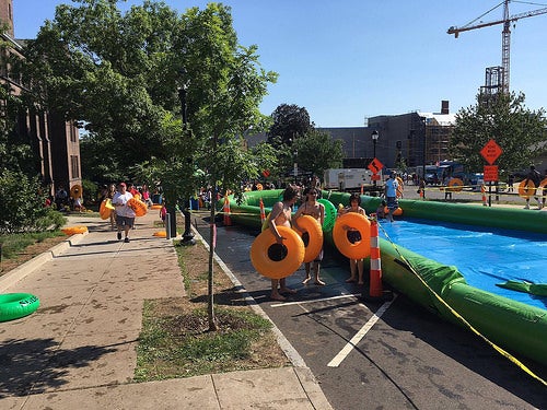 People with inner tubes walk along  the side of the slide.