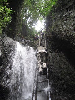 A student climbs down a ladder into an underground cavern.
