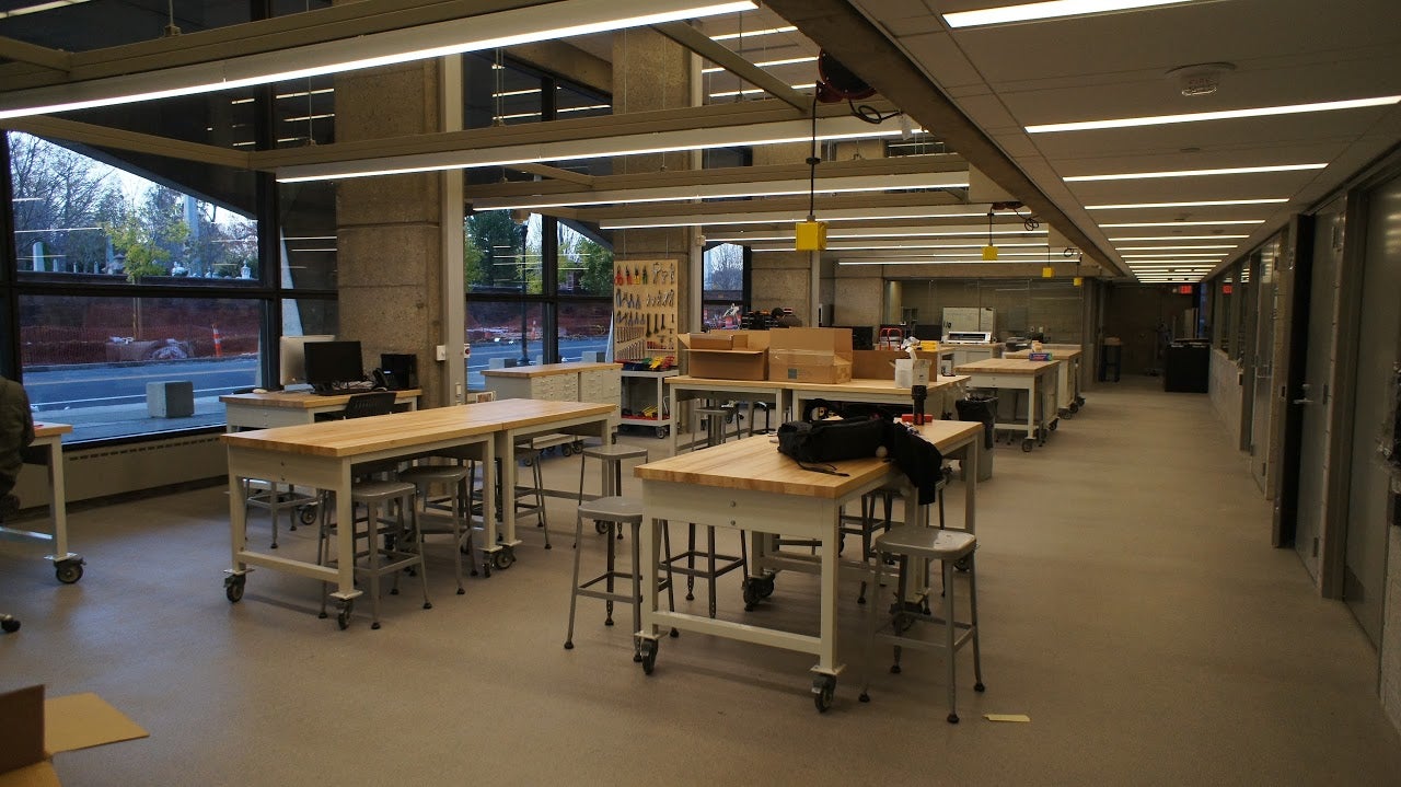 A room full of workbenches, with tools hanging on the walls.