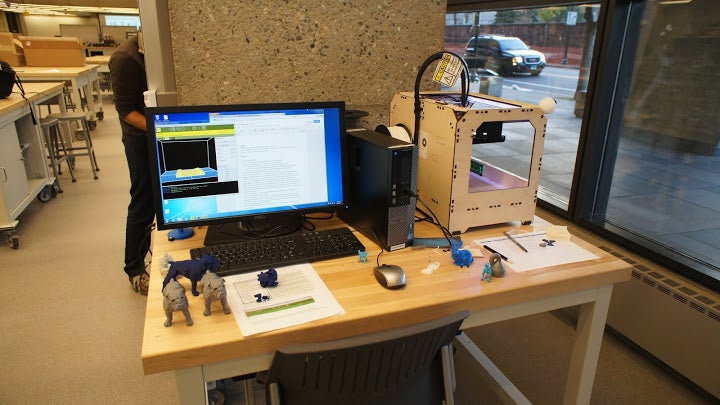 A workstation for 3D printing, decorated with 3D printed creations including several Yale bulldogs.