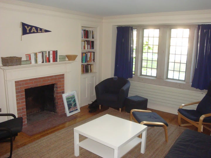 A Yale common room with bookshelves, comfy chairs, big windows and a fireplace.