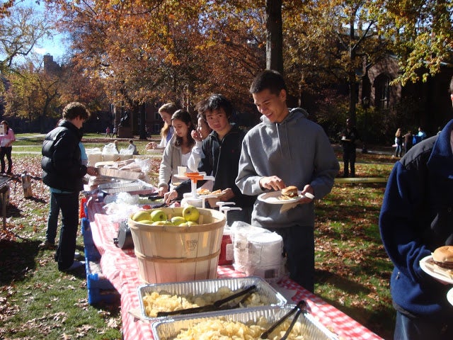 Freshmen students picking food from a picnic table.