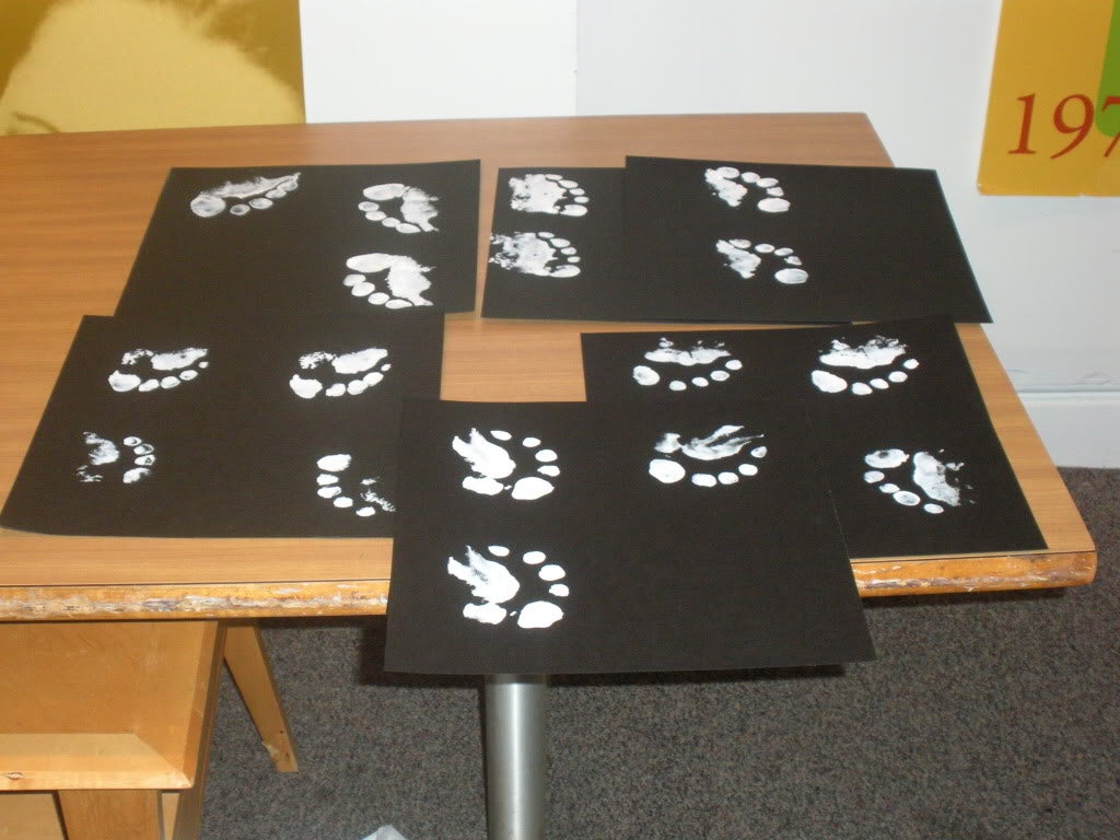 A collection of various students' paint footprints on paper.