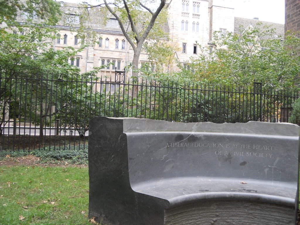 A curved marble bench, inscribed with &quot;A Liberal Education is at the heart of a civil society&quot;.
