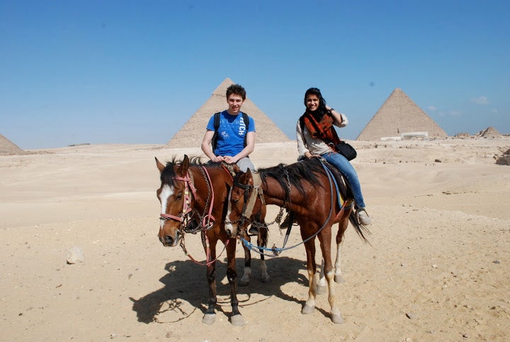 Author Snigdha and another student riding horses through the desert, with the Great Pyramids behind them.