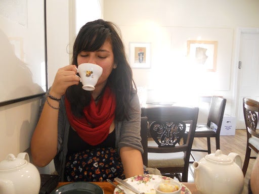 Michelle taking a sip from an ornamental teacup.