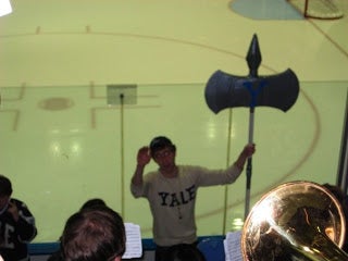 A student conducting the Yale Precision Marching Band with a double-bladed battle axe.