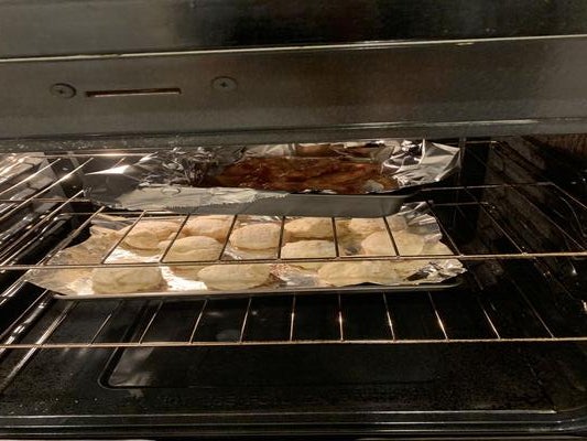 oven with bbq chicken and biscuits cooking inside