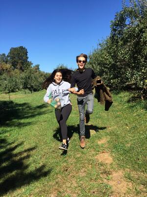 two people skipping with apples in hand in open field