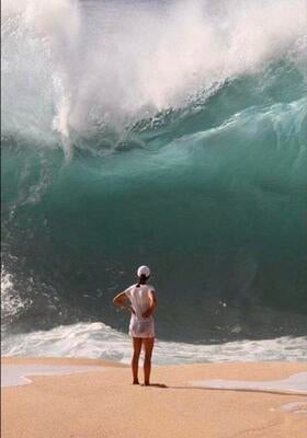 A woman staring at a large wave.