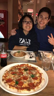 a pizza in front of two smiling friends