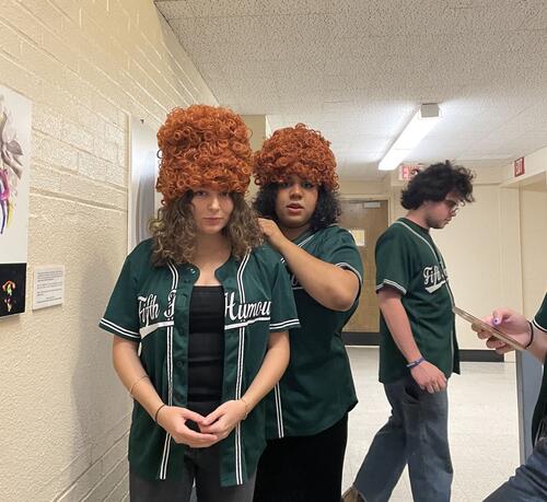 Some members of the Fifth Humour stack wigs backstage for a sketch where characters build a wig tower.
