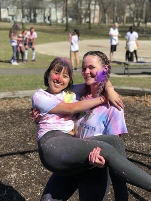 two girls smile together, covered in neon powder