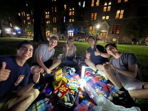 Five friends gathered on a picnic blanket full of snacks under the midnight darkness of Old Campus. 