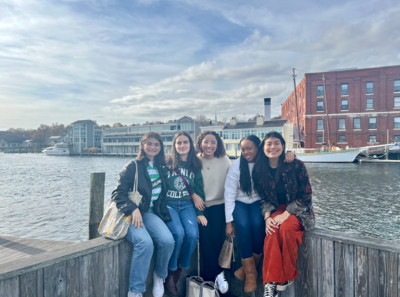 Five girls sitting in front of a harbor