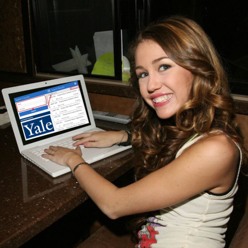 Miley Cyrus sitting at the computer smiling, looking at Yale's course selection website.