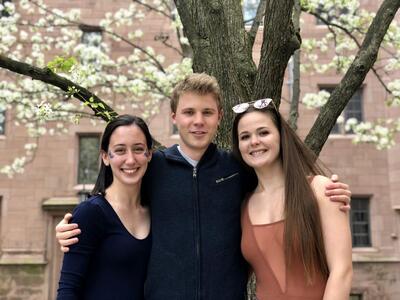3 people pose in front of a blooming tree