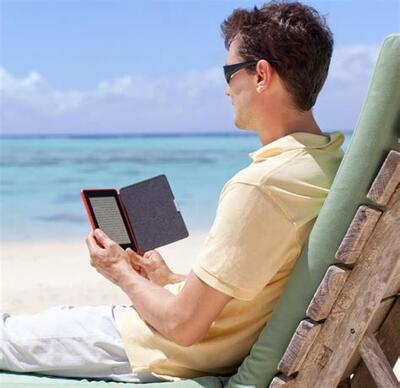 Man reading digital book on beach