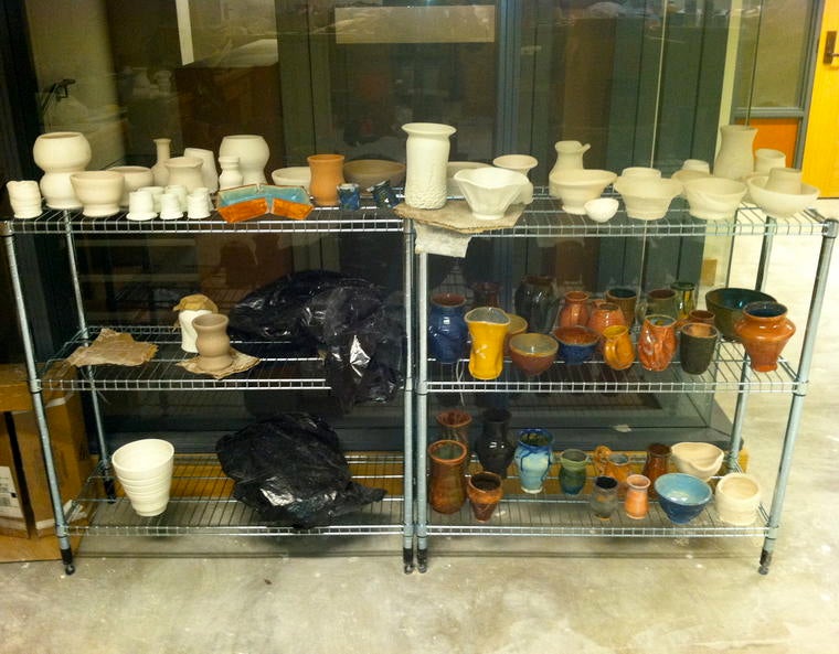 Ceramic cups, pots and vases on a drying rack.