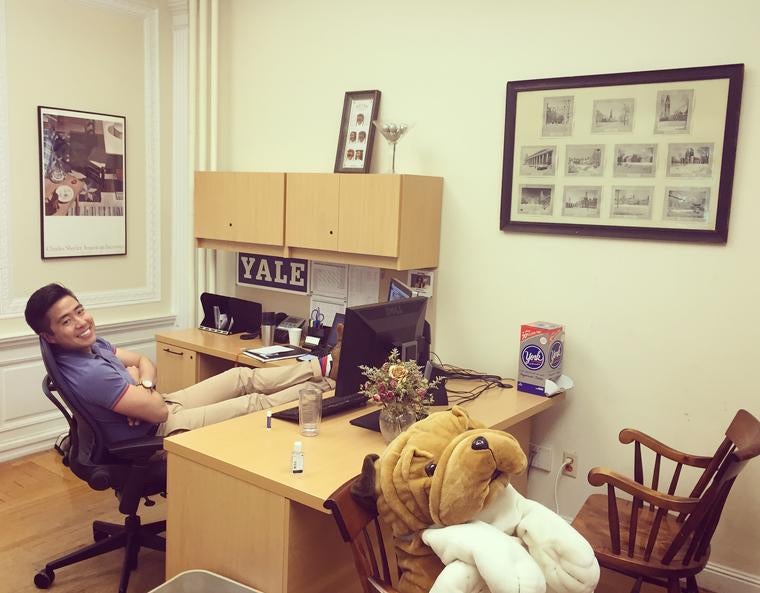 Photo of John Yi at his desk in the admissions office