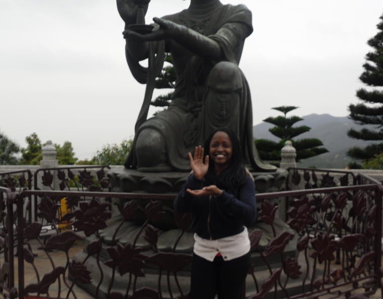 The author mimicking the pose of a Chinese statue behind her.