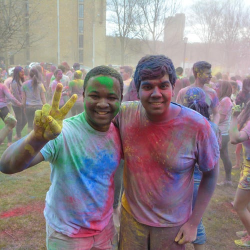 Two young men painted in bright colors, celebrating Holi, the Hindu spring festival.