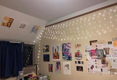 Yale dorm bedroom wall decorated with various posters, a collage, and fairy lights